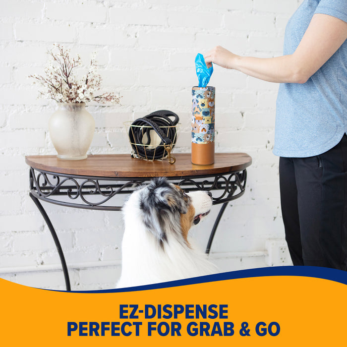 A person pulls a blue fresh-scent bag from the patterned Arm & Hammer Gotta Go Waste Bag Dispenser on a table, while a dog watches. Text below reads, EZ-Dispense Perfect for Grab & Go.