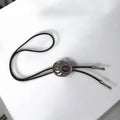 Two bear paw bolo ties with black braided leather cords: silver-tone faux turquoise bear claw slider and black stone bear paw pendant with antique metal tips.