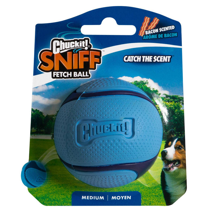 A Chuckit! Bacon Sniff Fetch Ball in blue packaging, labeled as a bacon scented dog ball. The package shows a dog, has a grassy park background, and features the phrases “Catch the Scent” and “Medium.” Brand: Chuckit!.