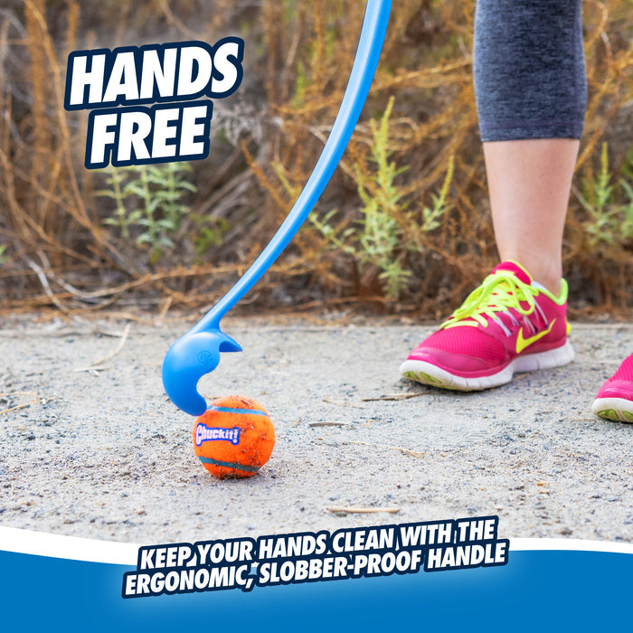 Wearing pink sneakers, a person uses the Chuckit! Junior 18M Dog Ball Launcher to pick up an orange Chuckit! ball from a dirt path. HANDS-FREE – Keep your hands clean with the ergonomic, slobber-proof handle.
