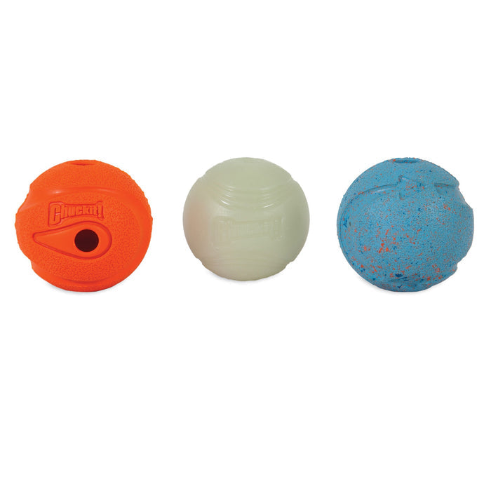 Three Chuckit! Medium Fetch Medley Dog Balls are side by side: an orange ball with a hole and logo, a plain white glow-in-the-dark ball, and a blue ball with orange speckles.