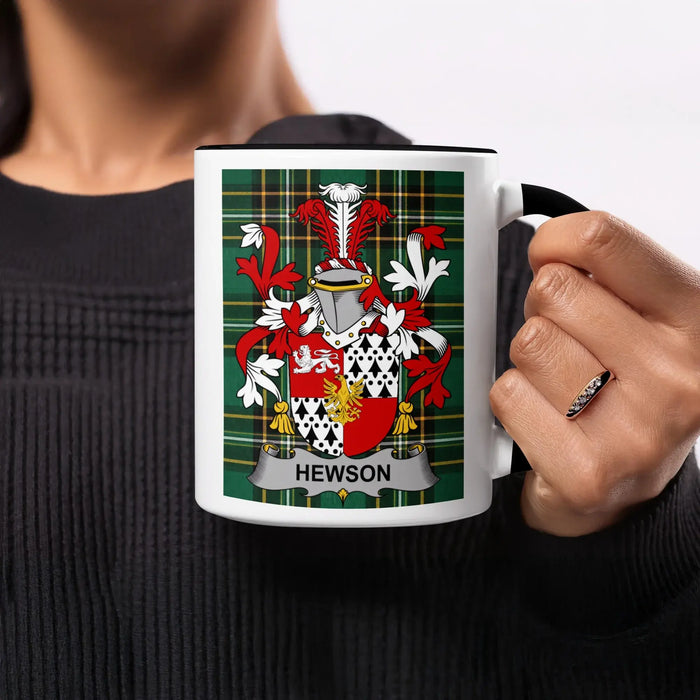 Hewson family crest on a white mug held by a person.
