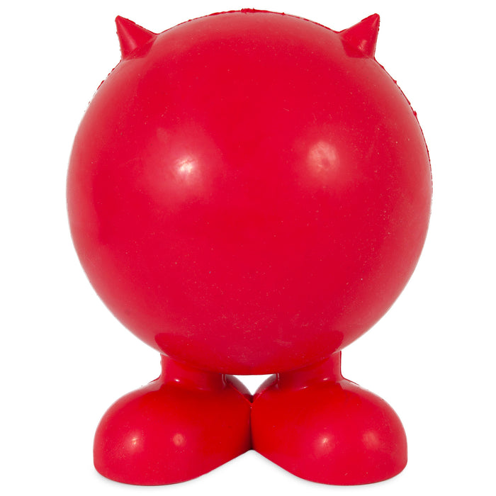 The JW Cuz Dog Toy by JW Pet is a round, bright red figure made from natural rubber, featuring small pointed horns on top and large feet at the bottom. It stands upright with no visible facial features or arms.
