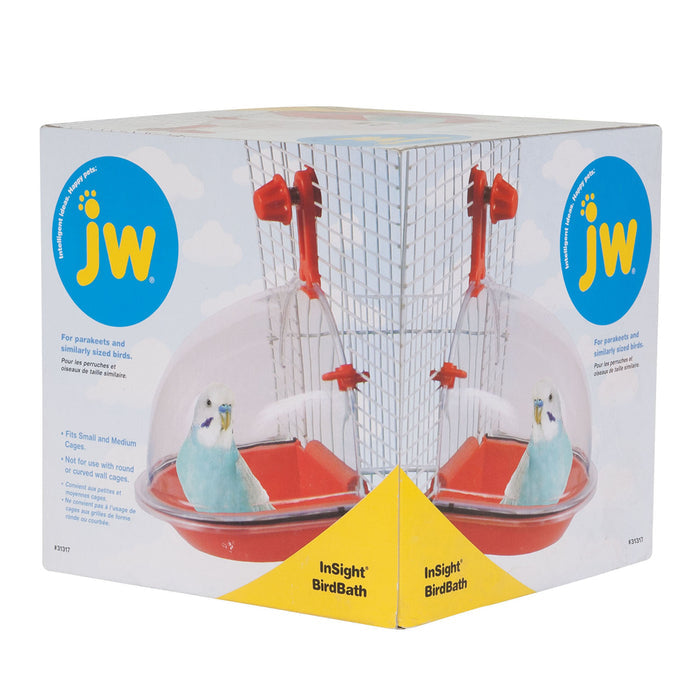 A JW Pet JW Insight Bird Bath box displays a small light blue parakeet using the red and clear plastic bird bath attached to a small cage, along with branding and product details on the packaging.