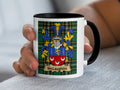 Black-accent McLaughlin mug held in a hand, showing the red crescent shield and blue-and-gold mantling.