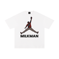 A white short-sleeve crewneck t-shirt featuring a graphic of Colton Cowser in orange and black orioles jersey mid-homerun rob, with the word 'MILKMAN' printed in bold black letters underneath.