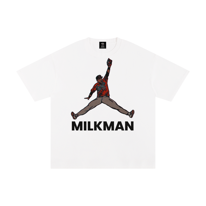 A white short-sleeve crewneck t-shirt featuring a graphic of Colton Cowser in orange and black orioles jersey mid-homerun rob, with the word 'MILKMAN' printed in bold black letters underneath.