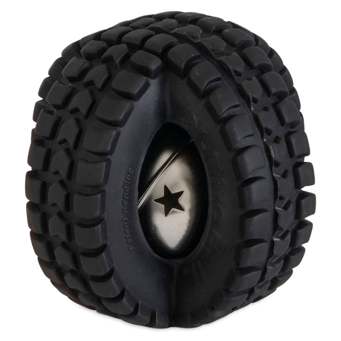 A close-up reveals a black rubber tire with rugged treads encircling a shiny metal sphere with a star-shaped cutout, resembling the Pet Qwerks Jingle X-Tire Ball by Petqwerks. This design contrasts matte rubber and reflective metal for an eye-catching pet toy.