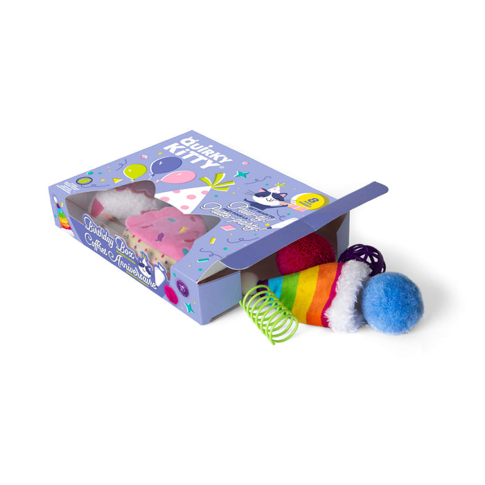 The Quirky Kitty Birthday Box 8pk – Birthday & Gotcha Day Cat Toy Gift Set by Quirky Kitty features a purple, cartoon-decorated box with assorted cat toys: rainbow ball, green spring, blue pom-pom, and pink ice cream-shaped toy.