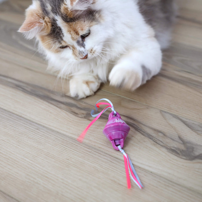 A fluffy white and brown cat paws at a Quirky Kitty Chilly Chasers 2pk – Freeze & Play Cat Toy Set by Quirky Kitty, with colorful ribbons, on a wooden floor.