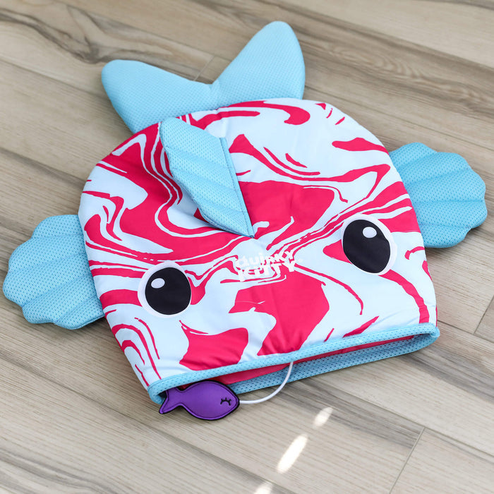The Quirky Kitty Fish Cooling Mat – Ocean-Themed Cat Play Mat by Quirky Kitty features a red and white swirled fish design, blue fins, cartoon eyes, and a small attached purple toy—perfect for keeping cats cool on any wooden floor.