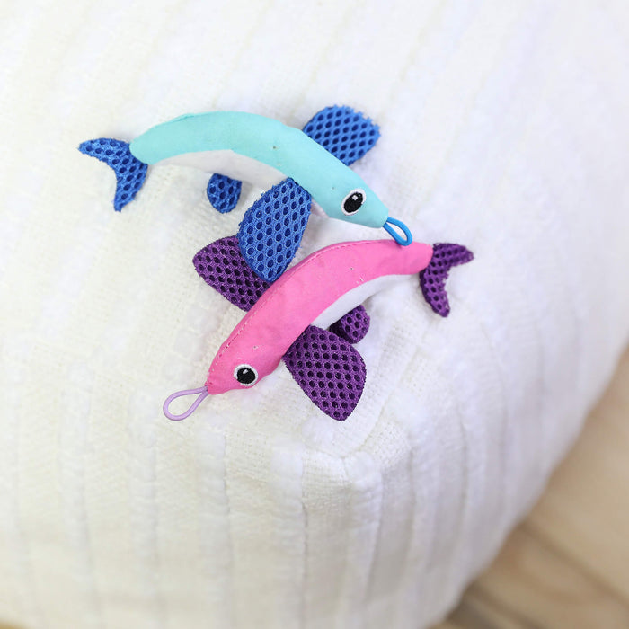 The Quirky Kitty Flying Fish 2pk—Interactive Catnip Cat Toys with Slingshot—features a blue and a pink fish, each with purple fins, large stitched eyes, and looped mouths on a white textured surface.