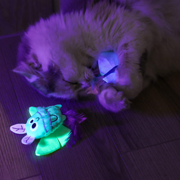 A cat plays on a wooden floor with Quirky Kitty Luna Bugs 2pk—glow-in-the-dark, catnip & silvervine toys, including a glowing blue bug and a forest-inspired bug that both light up under UV or black light.