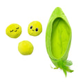 Three round yellow plush toys, two with embroidered faces, sit beside a green Quirky Kitty Pea Pawd Kicker – Large Catnip Cat Kicker Toy with a feather at one end, all on a white background.