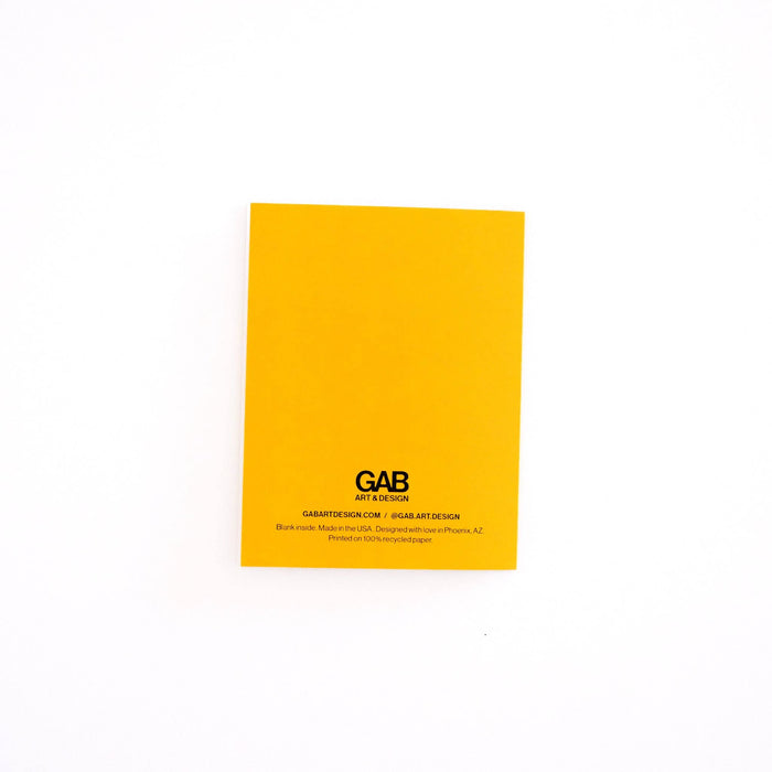 A bright yellow rectangular card or notebook cover with black printed text reading GAB art design, photographed on a plain white background.